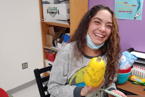 An Eastlake High School student smiles while showing the pumpkin she decorated