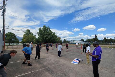 Eastlake High School students play games together outdoors. An Eastlake teacher watches a game of badminton.