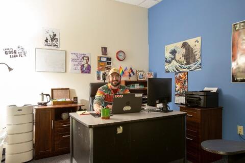 A staff member of Eastlake High School sits at a desk in his office.