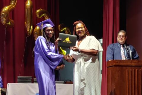 A smiling Eastlake staff member presents a graduating student with her diploma at Eastlake High School in Colorado Springs.