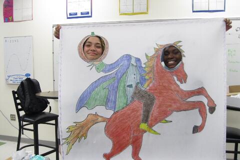 Two Eastlake High School students poke their faces through a cut out hole in a large poster drawing of a horse and the headless horseman.