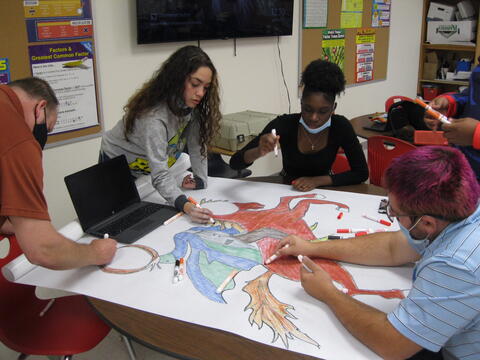 3 Eastlake High School students and a staff member work together on a collaborative drawing project.