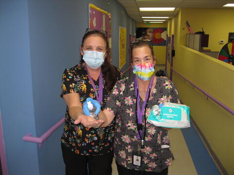 Two members of the Eastlake High School community smile at the camera, holding hand sanitizer and disinfectant wipes.