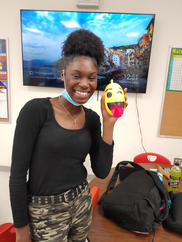 An Eastlake High School student poses with an emoji she created using a mini pumpkin. 