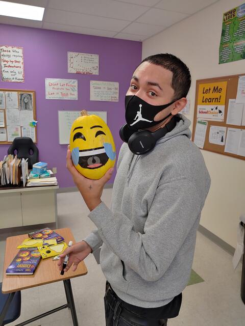 An Eastlake High School student shows off the pumpkin he turned into a cry-laughing emoji.