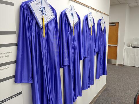 4 brilliant purple/blue graduation gowns and caps hang at the Eastlake High School 2022 graduation ceremony.