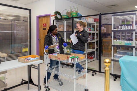 Two staff members at Eastlake High School share a laugh while preparing lunch for students. 