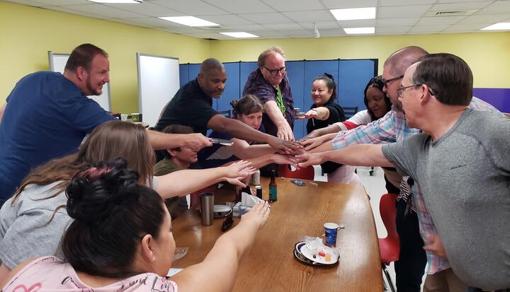  Ten Eastlake High School teachers place their hands together in a circle in a show of teamwork