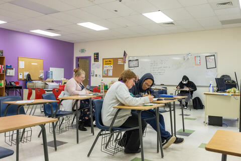 An Eastlake High School teacher and student work together at desks in the forefront of the image. There are other teachers and students working independently in the classroom.